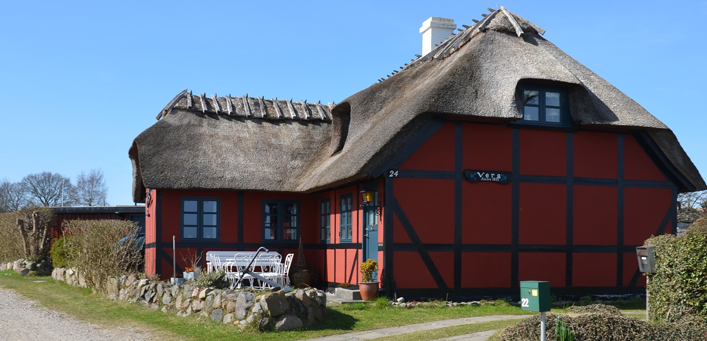 Rødt bindingsværkshus på grusvej