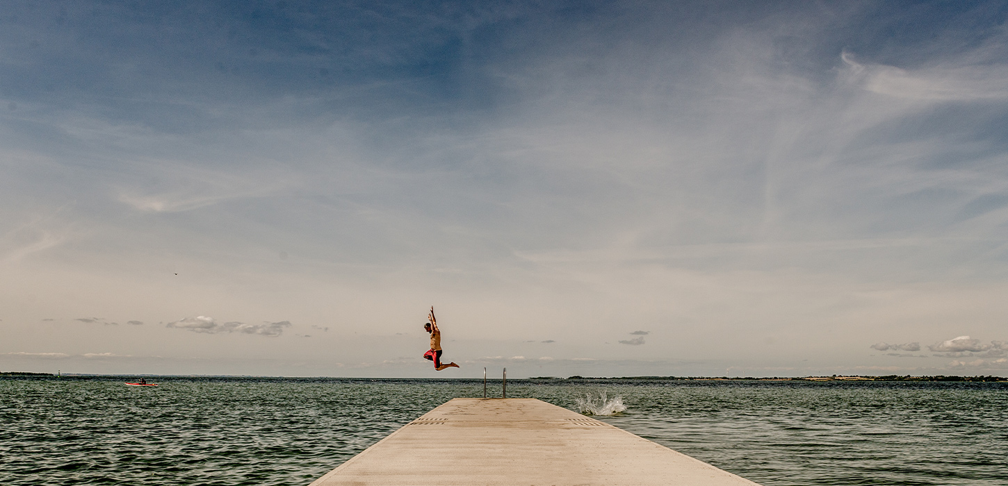 Far og søn springer i vandet fra badebro