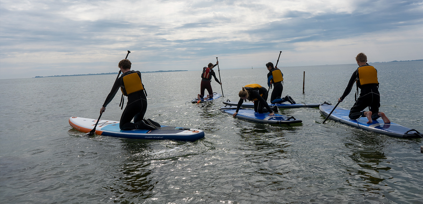 Fem unge mennesker på SUP boards ved Rudkøbing