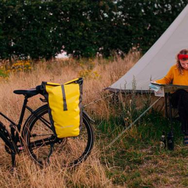 Kvinde sidder og kigger på et kort foran et glampingtelt